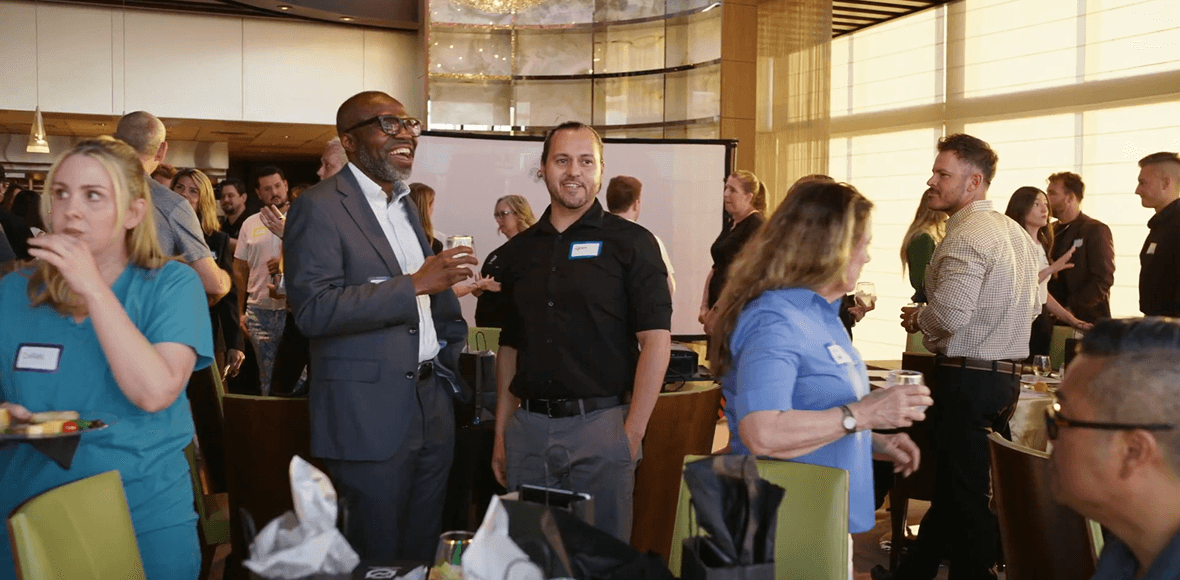 A diverse group of people socializing and networking at a lively indoor event, with many holding drinks and food.